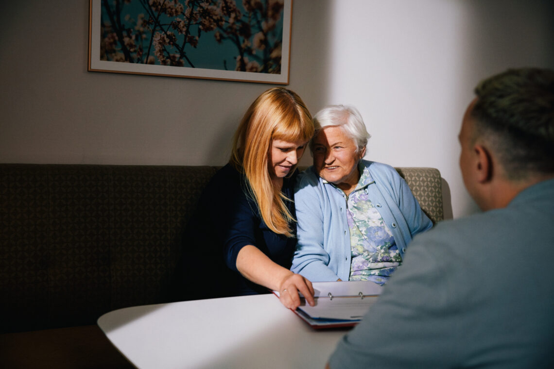 Ältere Dame und Tochter haben Planungsgespräch mit Pflegekraft