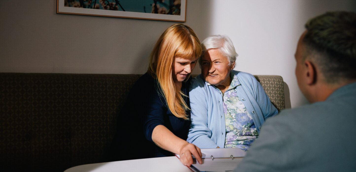 Ältere Dame und Tochter haben Planungsgespräch mit Pflegekraft