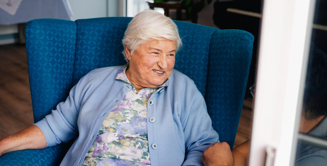 Ältere Dame unterhält sich fröhlich mit ihrem Pfleger