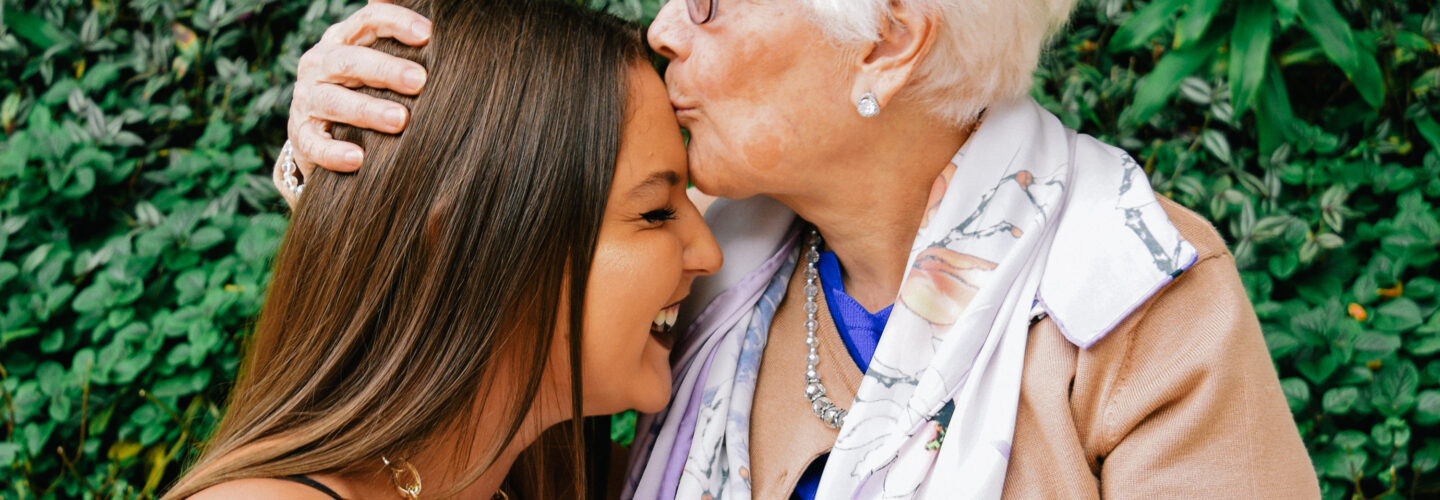 Oma gibt ihrer Enkelin einen Kuss auf die Stirn