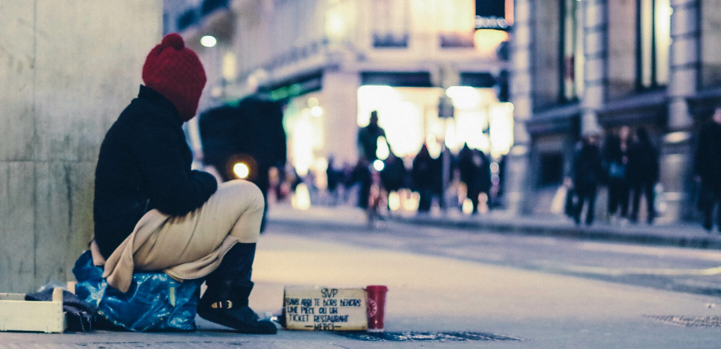 Obdachlose Person sitzt bei Nacht auf der Straße