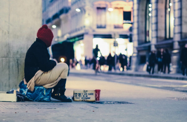 Obdachlose Person sitzt bei Nacht auf der Straße