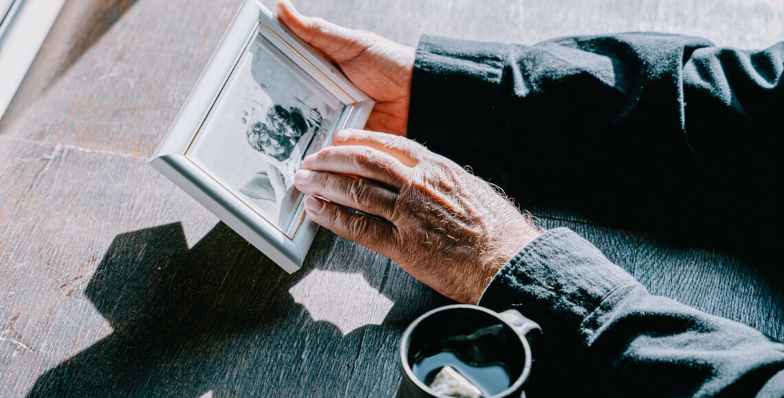 Ein Rentner hält ein gerahmtes Jugendfoto in Händen.