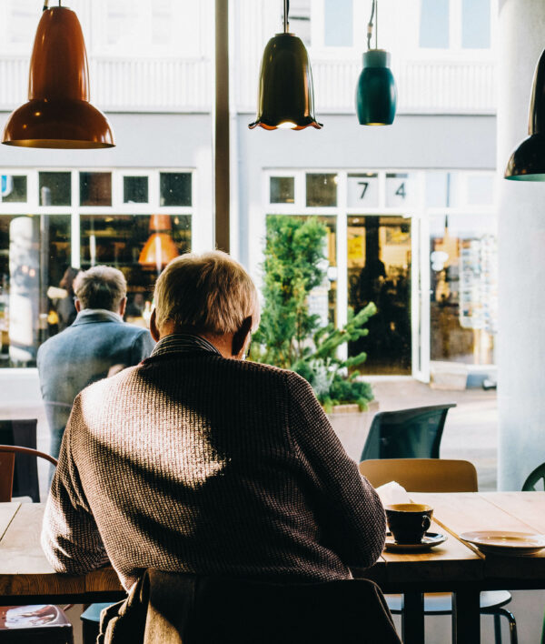 Ein Senior sitzt allein in einem Café